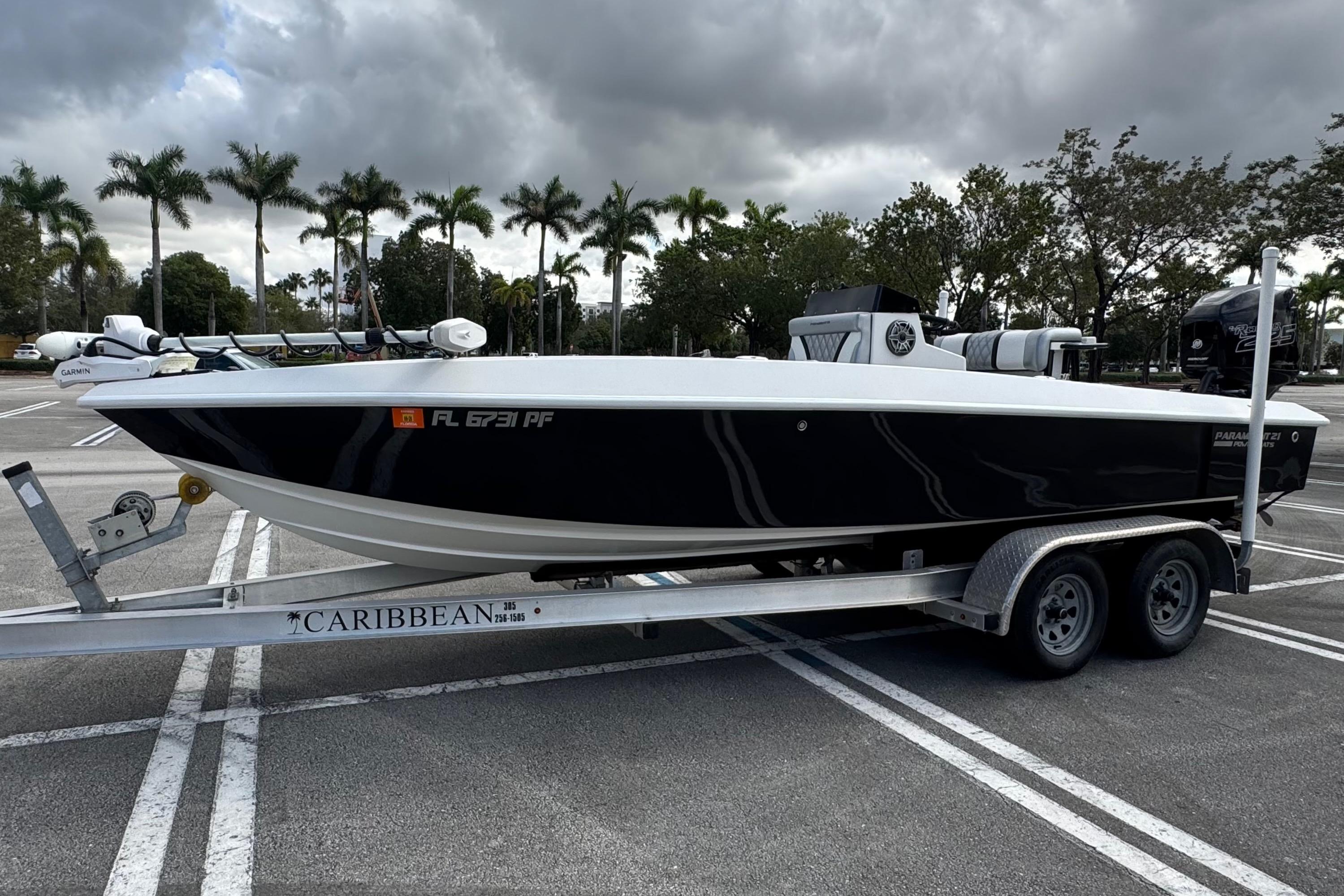 2010 Paramount Sportfisherman 21' boat on trailer, parked under cloudy sky with palm trees.