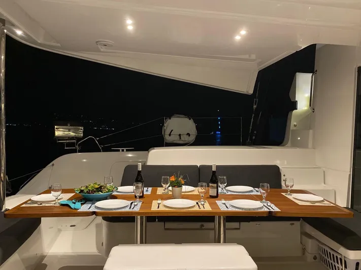 Out Of The Blue Yacht Photos Pics Luxurious Lagoon 50 yacht dining setup at night, featuring elegant tableware and ambient lighting.
