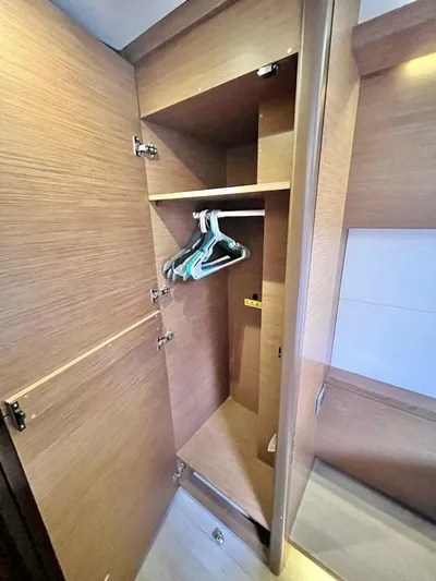 Out Of The Blue Yacht Photos Pics Wooden wardrobe interior on a 2019 Lagoon 50 yacht, featuring hangers and shelves.