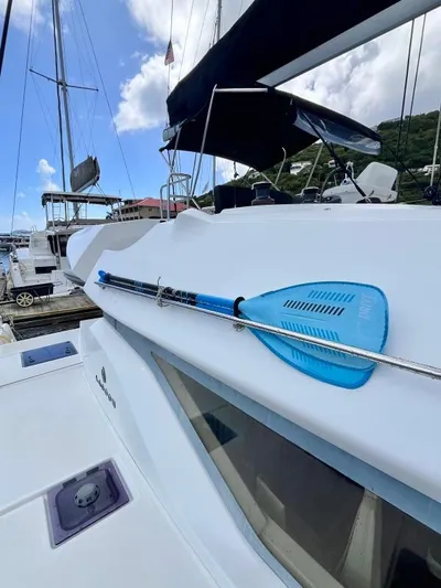 Out Of The Blue Yacht Photos Pics 2019 Lagoon 50 catamaran with blue paddle, docked at marina under clear sky.