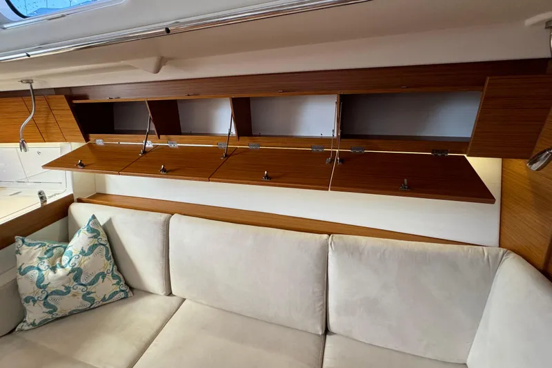 Vamoosh Yacht Photos Pics Interior of 2012 X-Yachts XP-44 with open wooden cabinets above a white sofa.