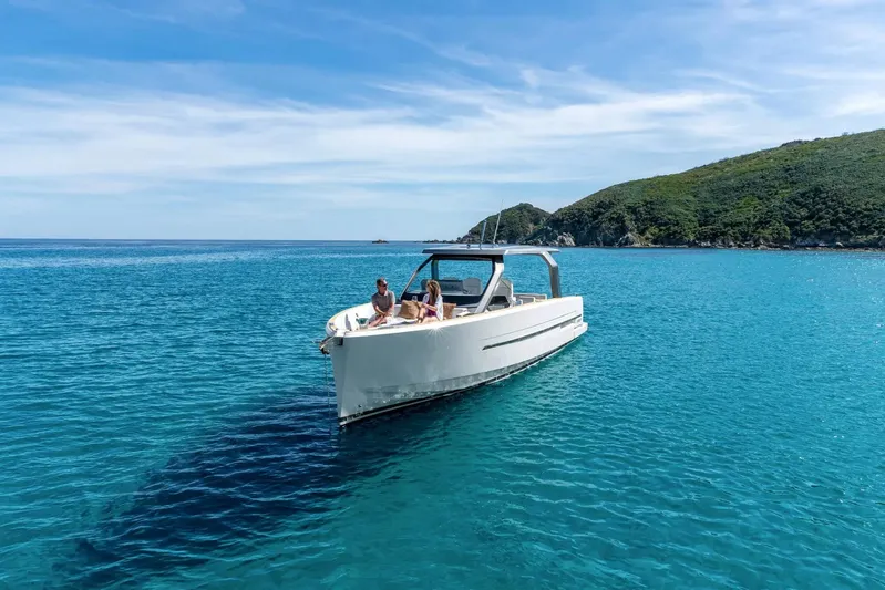  Yacht Photos Pics 2026 Fjord 39 XL yacht cruising in clear blue waters near a lush green island.