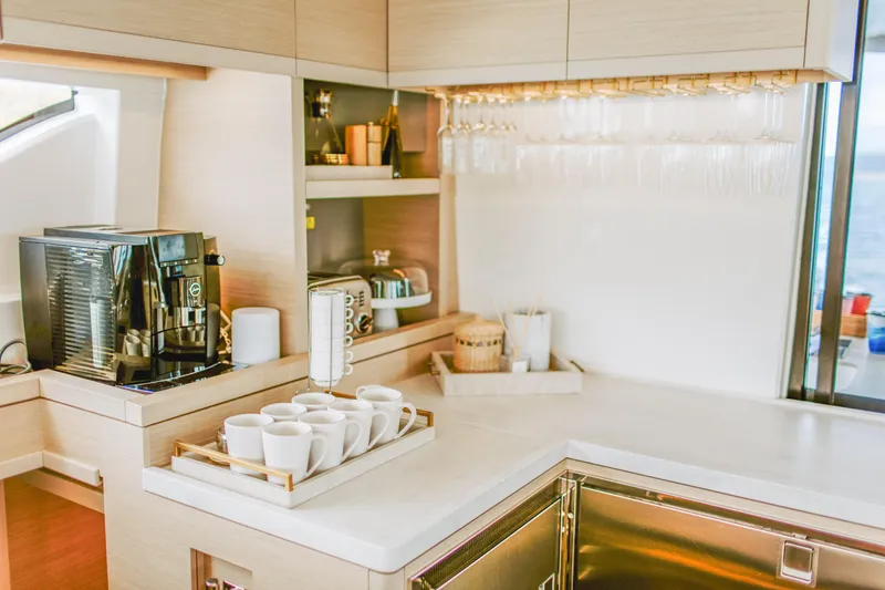 Wanderlust Yacht Photos Pics Modern kitchen interior on 2023 Lagoon 50 yacht with coffee maker and glassware.