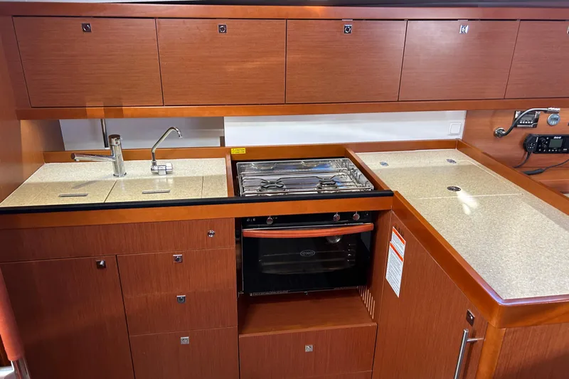  Yacht Photos Pics 2014 Beneteau Oceanis 41 yacht kitchen with wood cabinetry, sink, and stove.