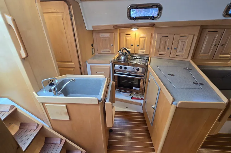 Irie Yacht Photos Pics Compact kitchen in 2018 Tartan 345 yacht with wooden cabinetry and modern appliances.