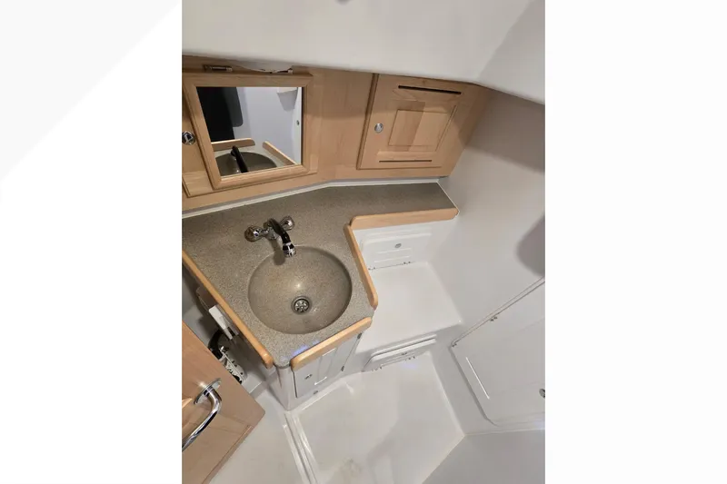 Irie Yacht Photos Pics Compact bathroom in 2018 Tartan 345 yacht with sink, mirror, and wooden cabinetry.