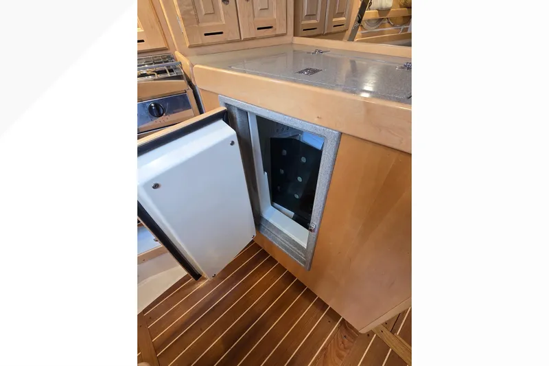 Irie Yacht Photos Pics Open refrigerator in Tartan 345 yacht kitchen, showcasing wooden cabinetry and flooring, 2018 model.