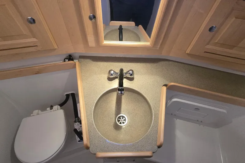 Irie Yacht Photos Pics 2018 Tartan 345 yacht bathroom with sink, mirror, and wooden cabinetry.
