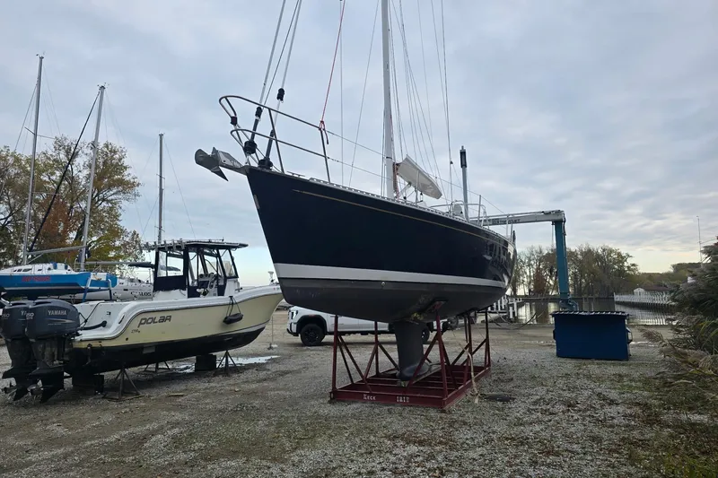 Irie Yacht Photos Pics 2018 Tartan 345 sailboat on dry dock beside a motorboat, overcast sky.