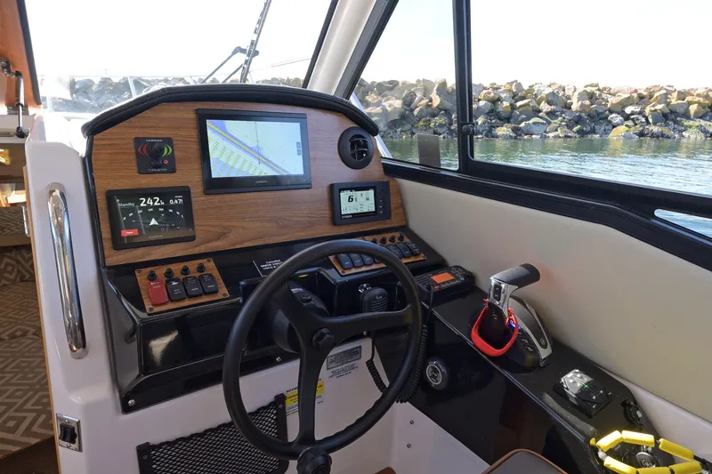 Cancelled Yacht Photos Pics 2024 Cutwater C-248 Coupe helm with navigation screens and controls, overlooking rocky shoreline.