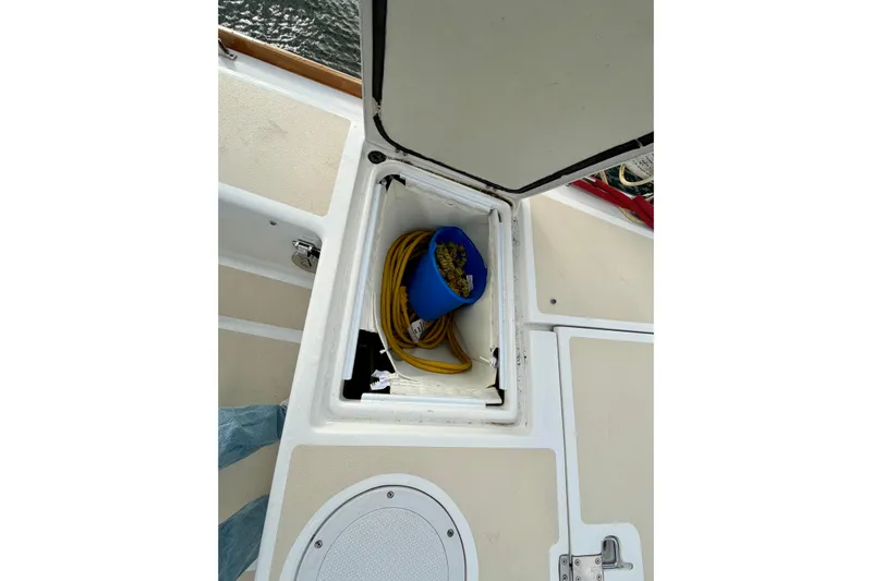 Kittywake Yacht Photos Pics Open storage compartment on 1996 J Boats J/42 sailboat deck with blue bucket and yellow hose.