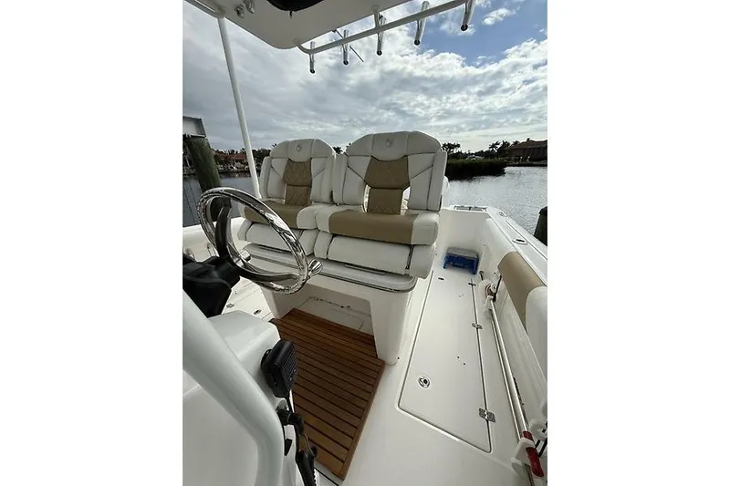  Yacht Photos Pics 2022 Edgewater 262CC boat interior with plush seating and steering wheel, docked by the water.