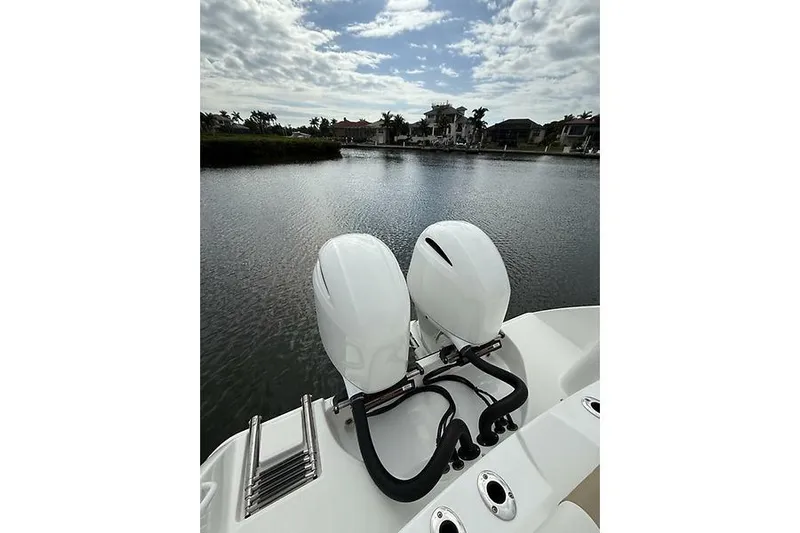  Yacht Photos Pics 2022 Edgewater 262CC boat with dual outboard motors on a calm waterway.