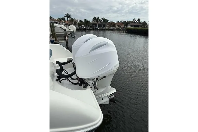  Yacht Photos Pics 2022 Edgewater 262CC boat with dual outboard motors on a calm waterfront.