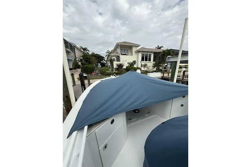  Yacht Photos Pics 2022 Edgewater 262CC boat docked near waterfront home under cloudy sky.