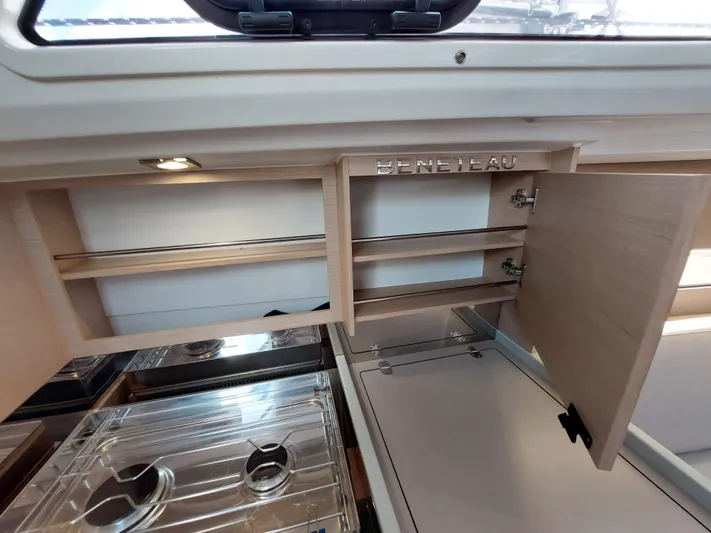 "makai" Yacht Photos Pics Interior of 2020 Beneteau Oceanis 30.1 yacht, featuring open wooden cabinets and a compact kitchen area.
