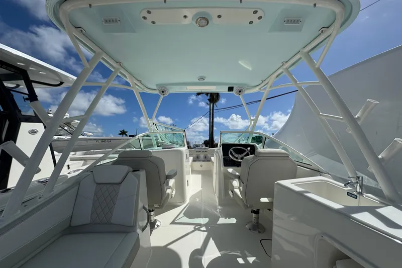 57582 230sd Sf Yacht Photos Pics 2026 World Cat 230 SD boat interior with seating, steering wheel, and sink under a clear sky.