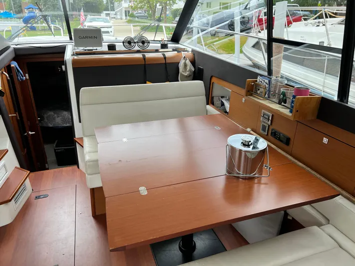  Yacht Photos Pics Interior of a 2017 Jeanneau NC11 boat with a wooden dining table and white seating.