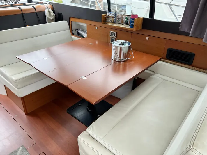  Yacht Photos Pics Interior of 2017 Jeanneau NC11 yacht with wooden table and white seating.