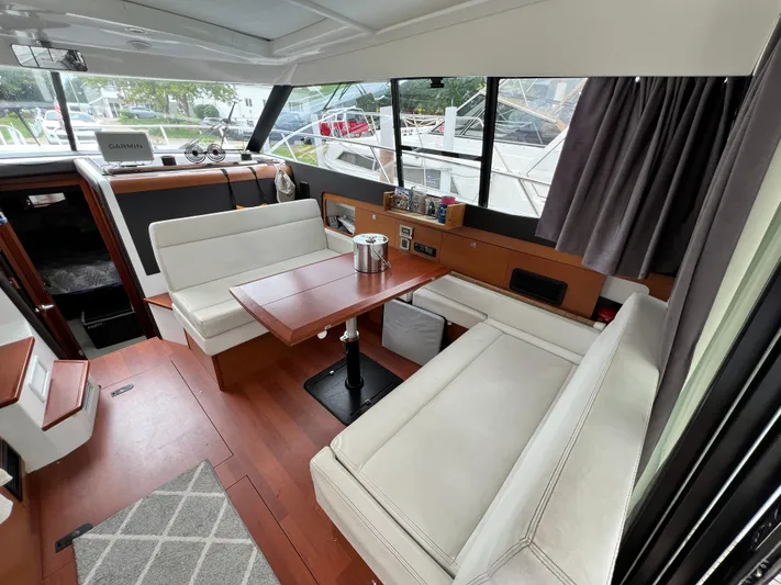  Yacht Photos Pics Interior of 2017 Jeanneau NC11 yacht with elegant seating and wooden table.