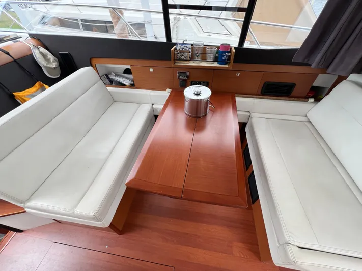  Yacht Photos Pics Interior of 2017 Jeanneau NC11 yacht with white seating and wooden table.