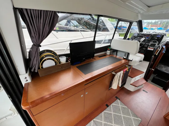  Yacht Photos Pics 2017 Jeanneau NC11 interior with helm, wooden cabinetry, and modern navigation equipment.