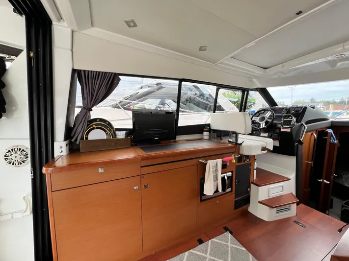  Yacht Photos Pics Interior of 2017 Jeanneau NC11 yacht with helm, wooden cabinetry, and modern design elements.
