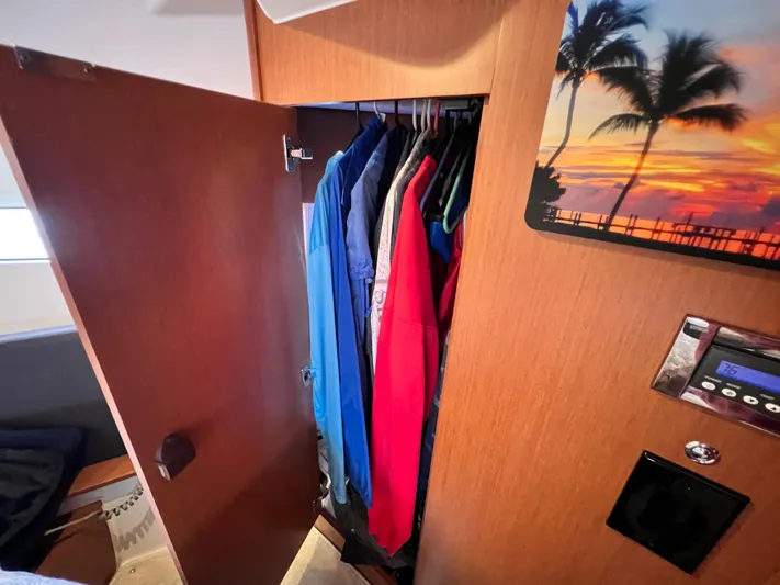  Yacht Photos Pics Closet interior on 2017 Jeanneau NC11 boat with hanging clothes and tropical wall art.