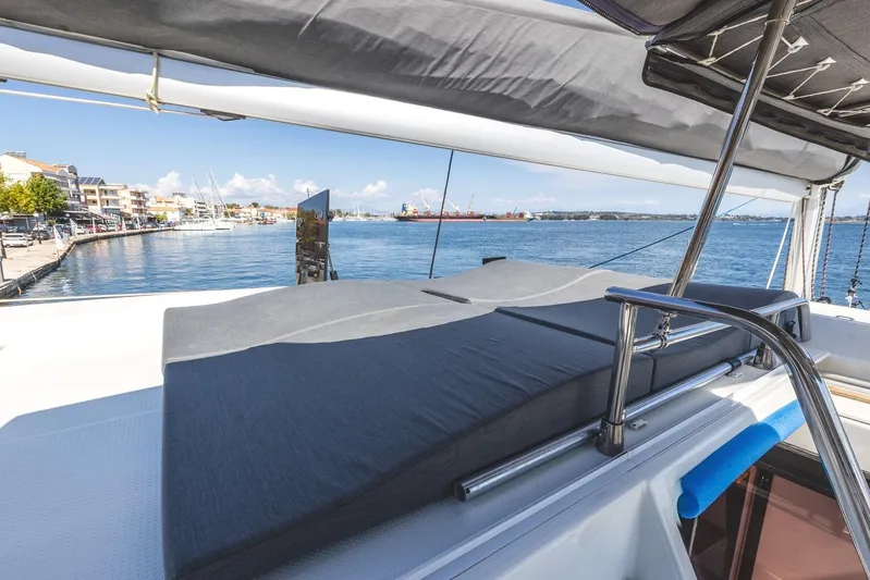  Yacht Photos Pics 2023 Fountaine Pajot Astrea 42 Maestro yacht with sunbathing area, docked by a scenic waterfront.