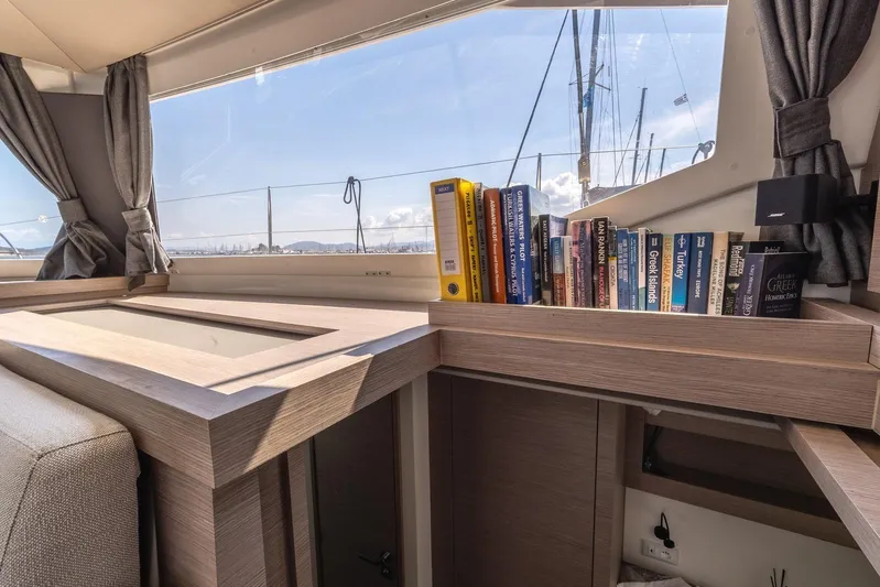  Yacht Photos Pics Interior of 2023 Fountaine Pajot Astrea 42 Maestro with bookshelf and scenic window view.