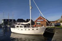 1984 Island Trader 40 sailboat docked near a harbor building under clear blue skies.