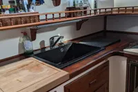 1984 Island Trader 40 yacht kitchen with wooden cabinets, sink, and shelves.