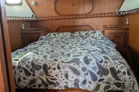 Cozy cabin interior of 1984 Island Trader 40 sailboat with paisley-patterned bedding.