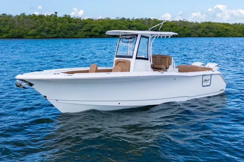  Yacht Photos Pics 2026 Sea Hunt Ultra 275 SE boat on blue water, near lush green shoreline.