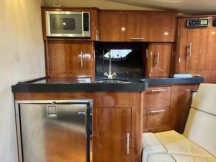 Clintessa Yacht Photos Pics 2012 Regal 35 Sport Coupe interior with kitchenette, featuring microwave, sink, and wooden cabinetry.