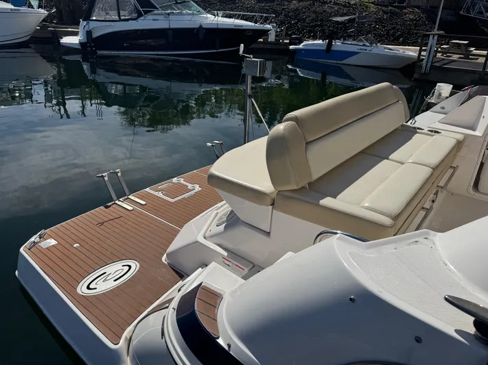 Clintessa Yacht Photos Pics 2012 Regal 35 Sport Coupe boat with beige seating and wooden deck at a marina.