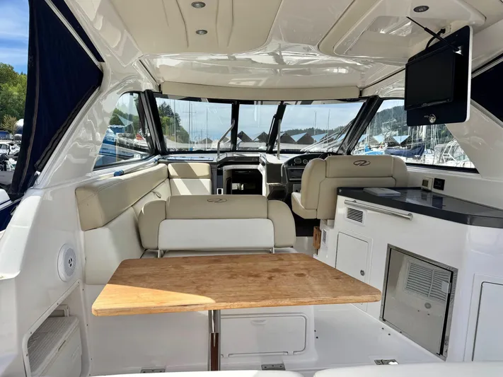 Clintessa Yacht Photos Pics 2012 Regal 35 Sport Coupe interior with seating, table, and TV in a marina setting.