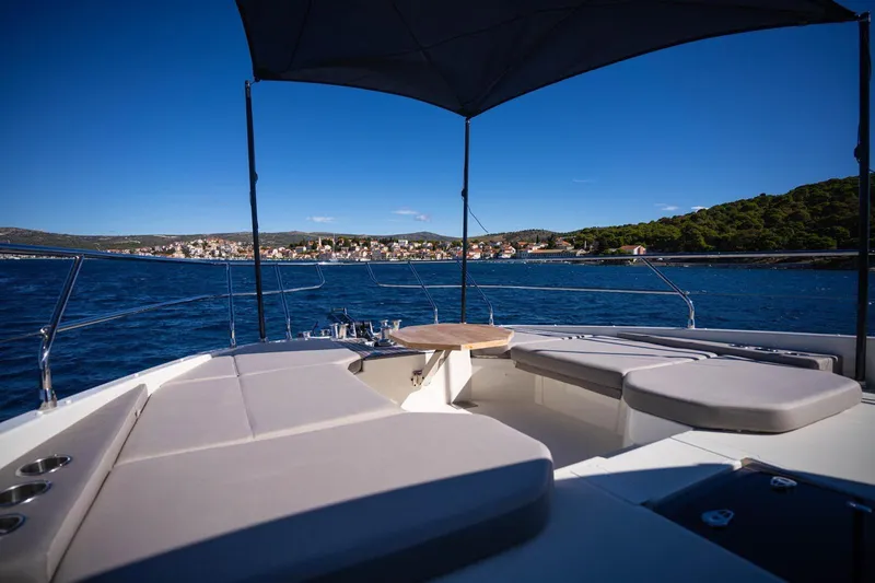 Leena Yacht Photos Pics Luxurious 2023 Prestige X60 yacht deck with seating, overlooking serene blue waters and coastal town.