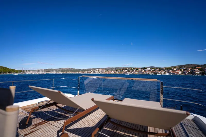 Leena Yacht Photos Pics Luxury yacht deck with sun loungers, Prestige X60, 2023 model, overlooking serene coastal town.