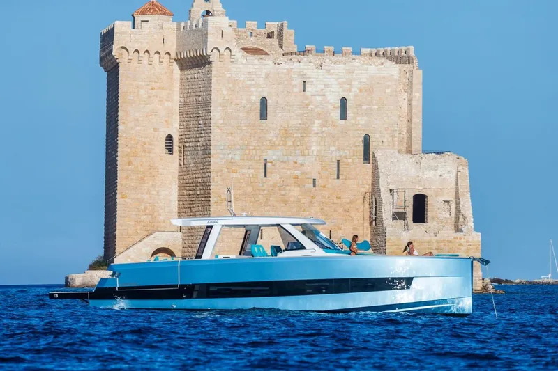  Yacht Photos Pics 2026 Fjord 490 OPEN yacht cruising near historic stone fortress on a sunny day.