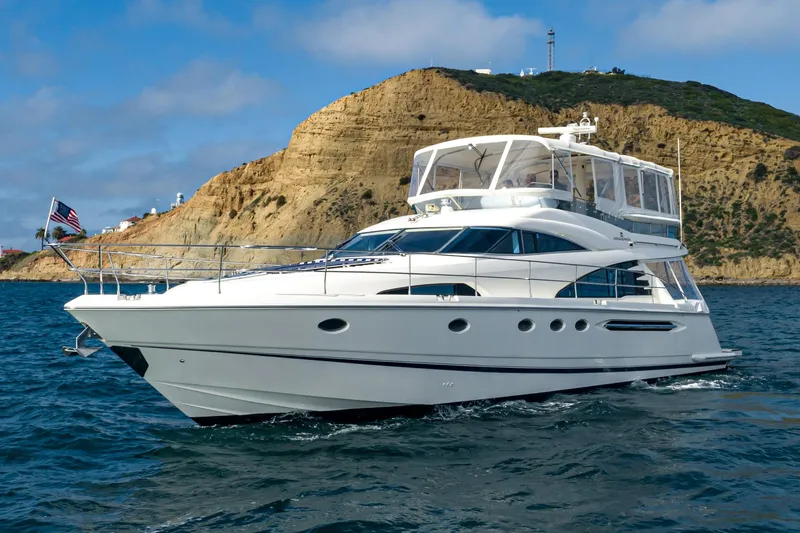 Desperado Yacht Photos Pics Luxury 2002 Fairline Squadron 58 yacht cruising near rocky coastline.