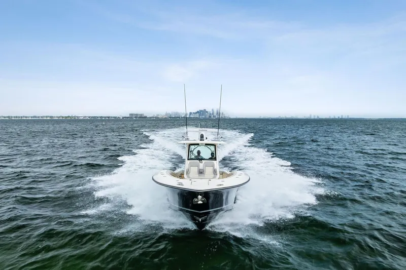 Prime Tyme Yacht Photos Pics 2020 Scout 355 LXF boat cruising on open water with city skyline in background.