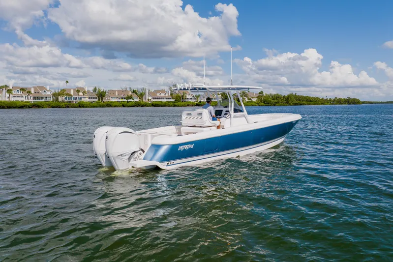  Yacht Photos Pics 2018 Intrepid 327 Center Console boat cruising on a sunny day, with scenic waterfront homes.