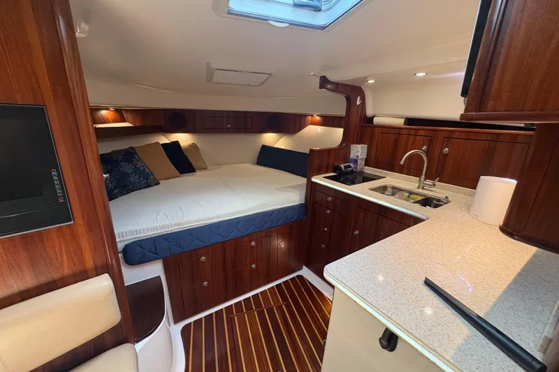 Happy Time 2 Yacht Photos Pics Luxurious interior of a 2011 Pursuit OS 375 Offshore boat with wood finishes and cozy bedding.