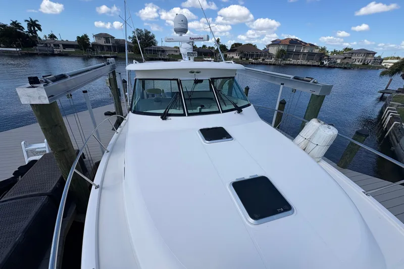 Happy Time 2 Yacht Photos Pics 2011 Pursuit OS 375 Offshore boat docked by waterfront homes under a blue sky.
