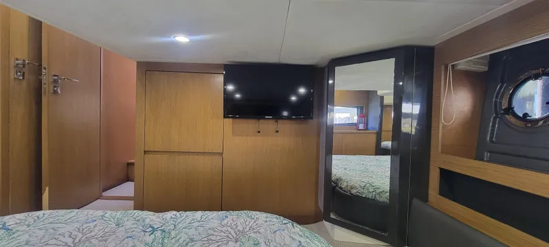  Yacht Photos Pics Interior of 2013 Azimut Atlantis 44 yacht cabin with TV, mirror, and wooden furnishings.