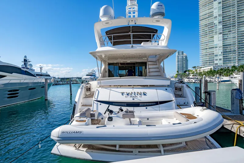 Twins Yacht Photos Pics 2009 Sunseeker Manhattan 70 yacht docked in a marina with cityscape background.