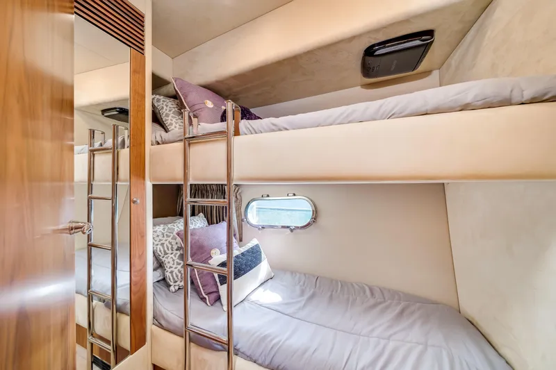 Twins Yacht Photos Pics Bunk beds in 2009 Sunseeker Manhattan 70 yacht cabin, featuring cozy bedding and a porthole window.