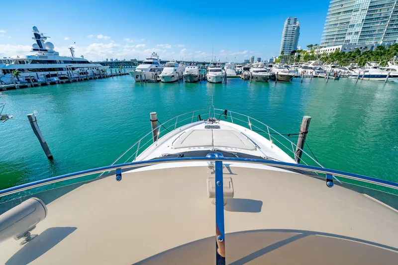 Twins Yacht Photos Pics 2009 Sunseeker Manhattan 70 yacht docked in a marina with turquoise water and luxury boats.