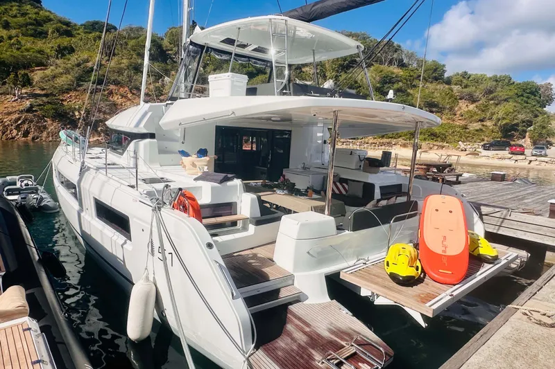  Yacht Photos Pics 2024 Lagoon 51 catamaran docked, featuring spacious deck and water sports equipment.